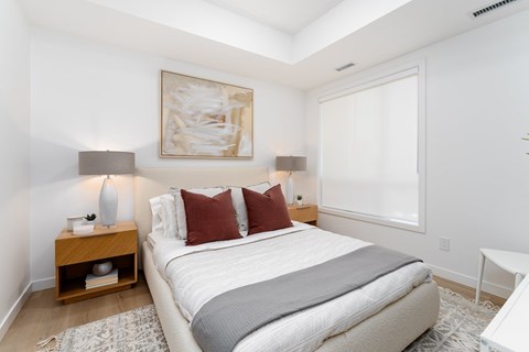 A bedroom with a large bed and a painting on the wall.