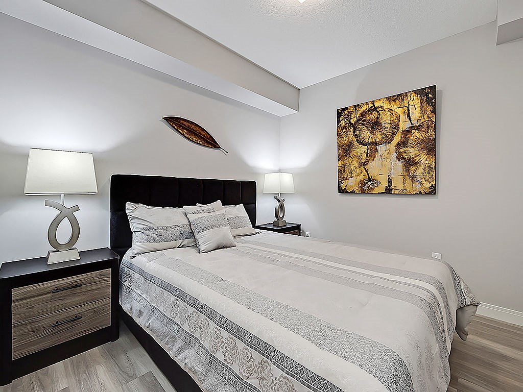 A bedroom with a bed, nightstand, and a painting on the wall.