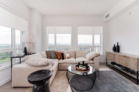 A living room with a white couch, a black coffee table, and a large window.