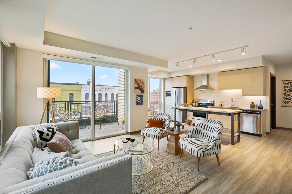 a living room with a couch and chairs and a kitchen with