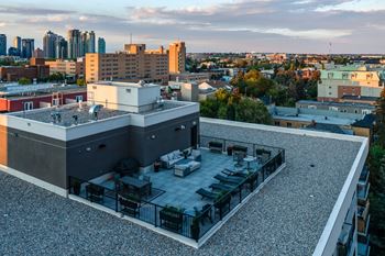 A rooftop patio with a table and chairs overlooks a city skyline.