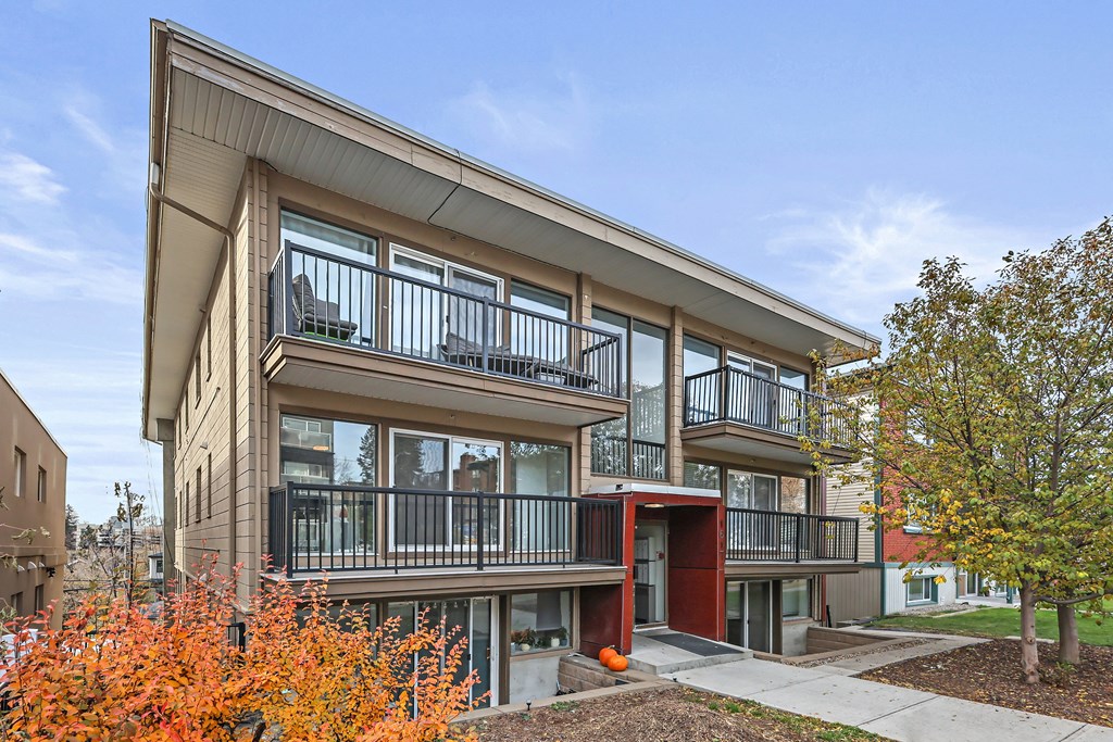A modern apartment building with a red door and balconies.
