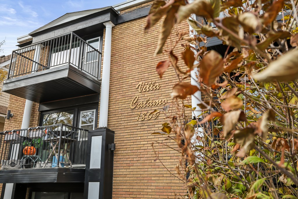 A balcony with a railing and a sign that says "Villas" on a brick building.
