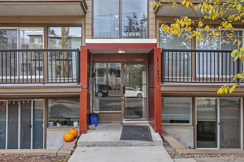 The entrance to a building with a red door and a black railing.