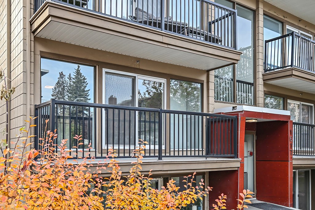 A balcony with a red door and a black railing.