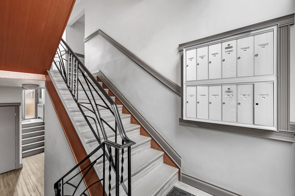 A staircase with a metal railing and a cabinet with drawers on the wall.