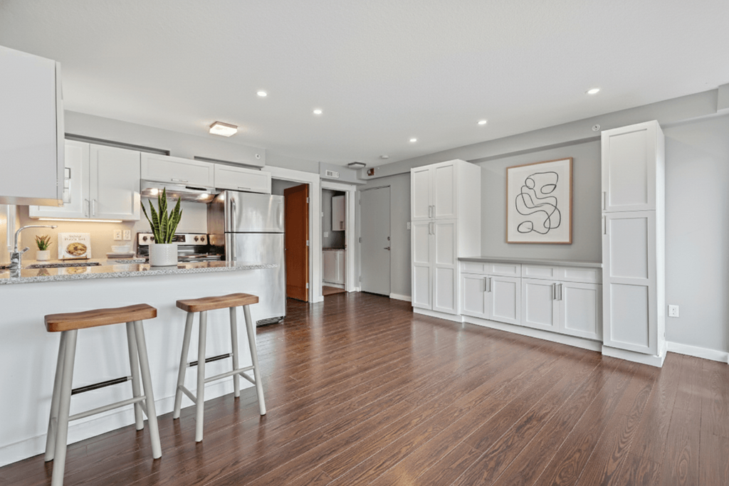 A kitchen with white cabinets and a wooden floor.