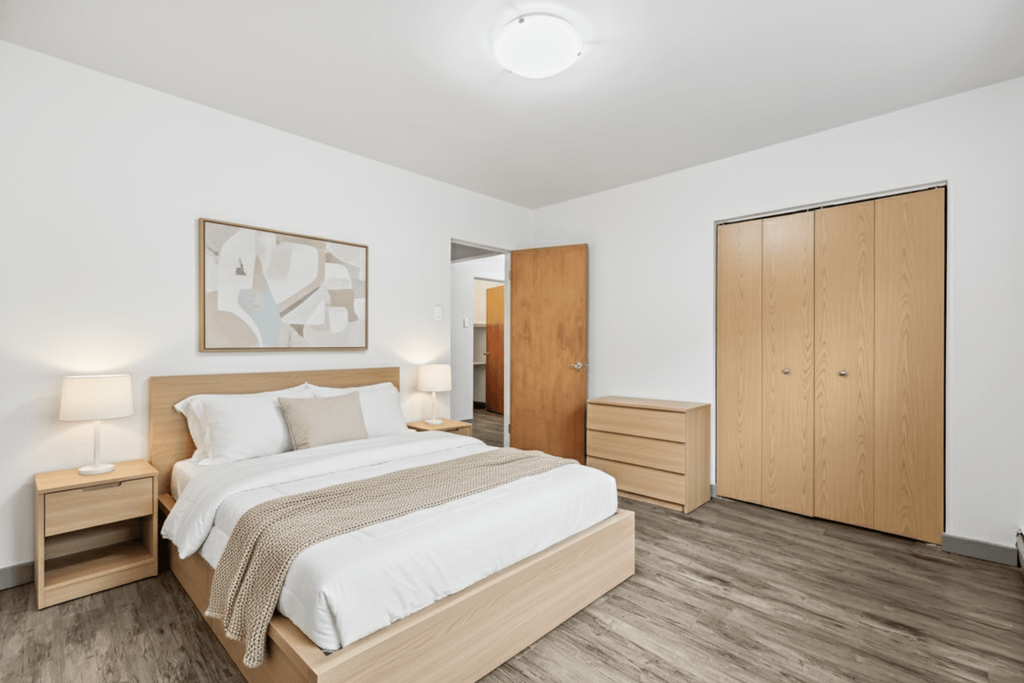 A bedroom with a bed, nightstand, and wardrobe.