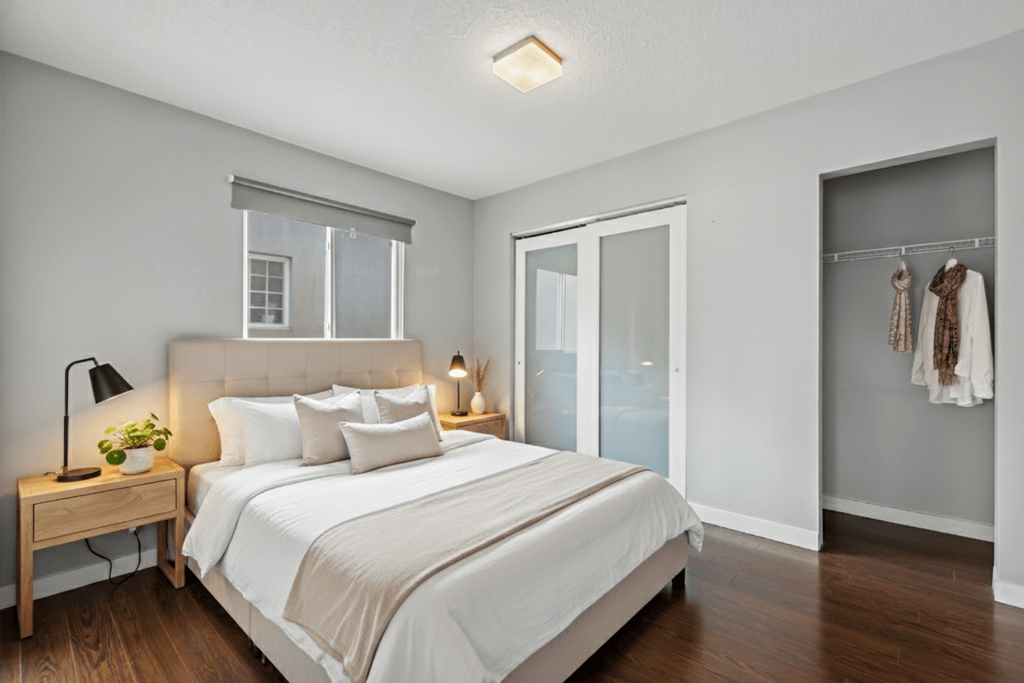 A bedroom with a large bed and a wooden nightstand with a plant on it.