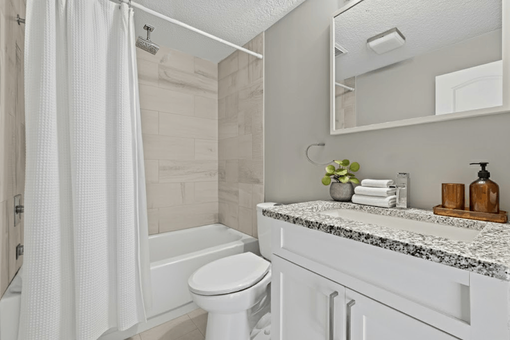 A white bathroom with a toilet, sink, and shower.