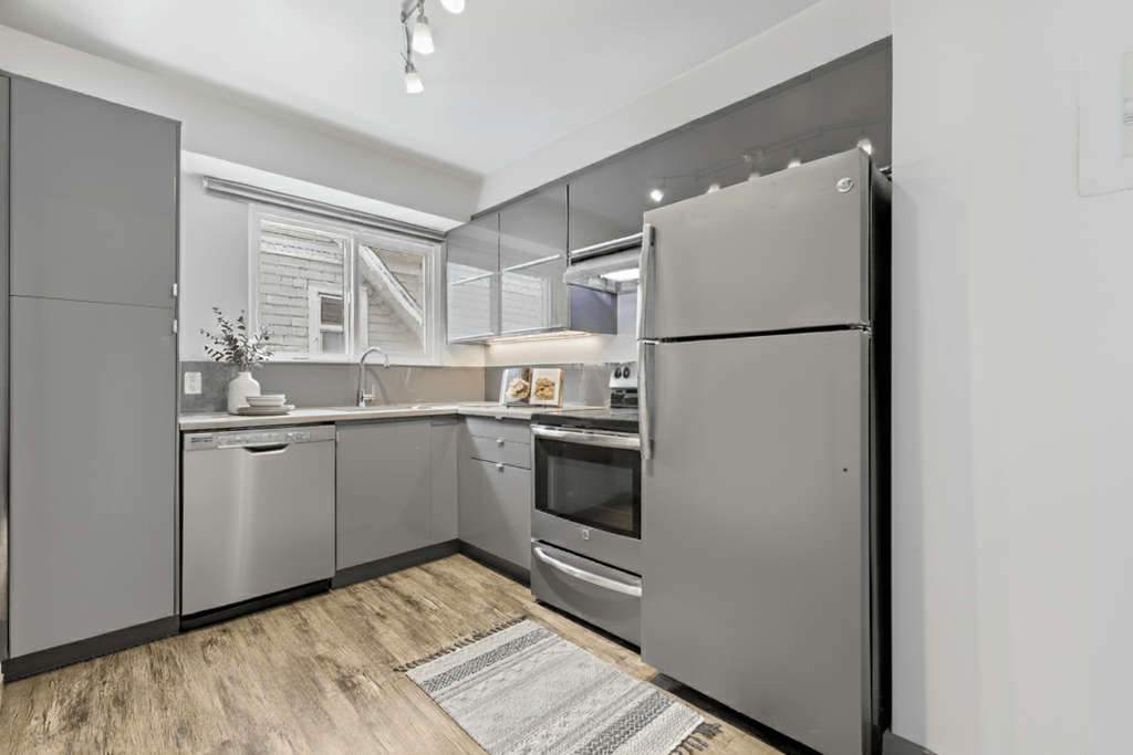 A modern kitchen with stainless steel appliances and wooden flooring.