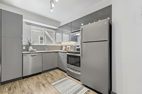 A modern kitchen with stainless steel appliances and wooden flooring.
