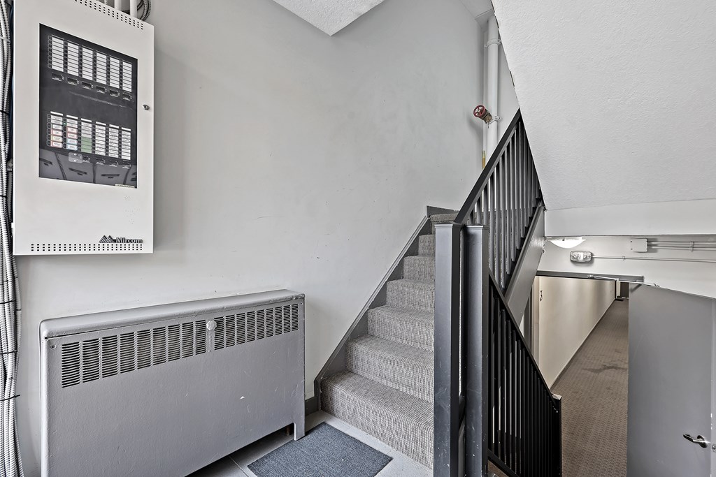 A staircase with a metal railing and a heater on the side.