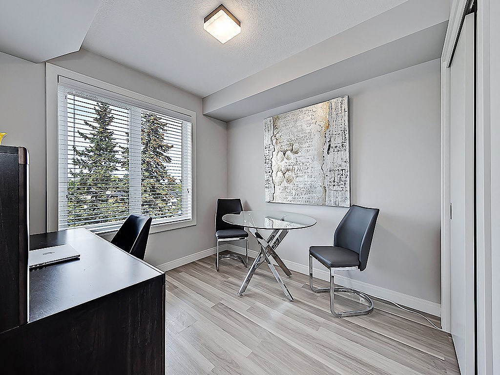 A room with a desk, chairs, and a painting on the wall.