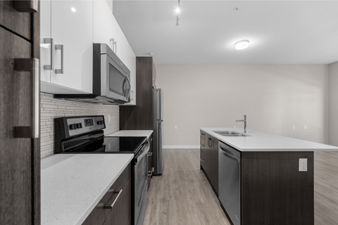 a renovated kitchen with white counter tops and stainless steel appliances