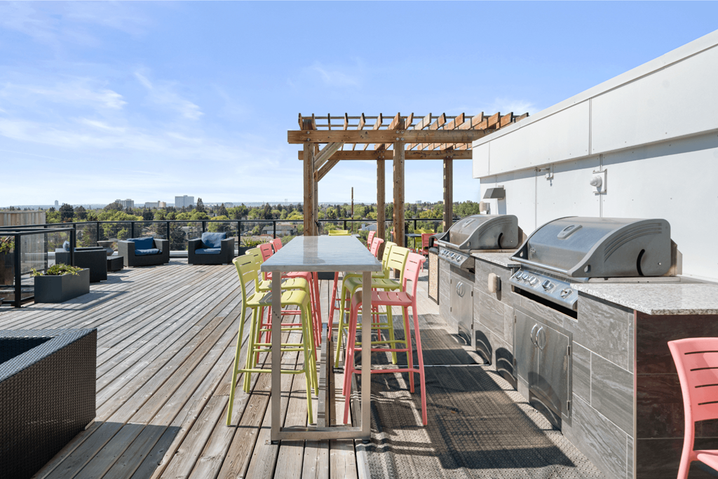 a patio with a table and chairs and a grill on a roof