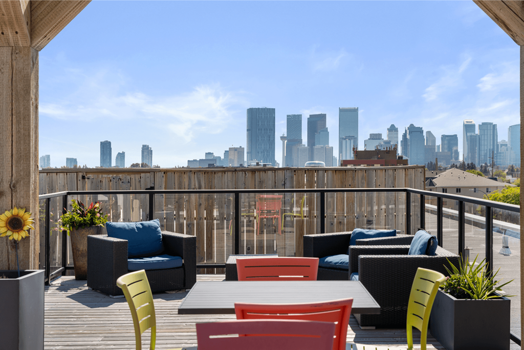a rooftop deck with furniture and a city skyline in the background
