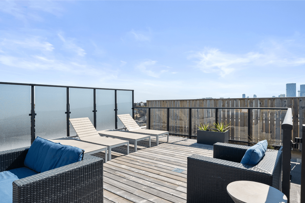 a rooftop deck with lounge chairs and a view of the ocean