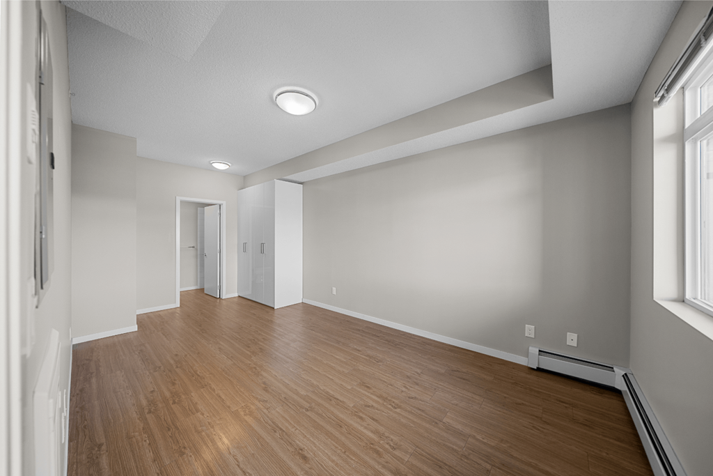 the living room is empty and has a wood floor and white walls