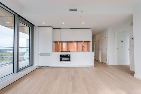 A modern kitchen with white cabinets and a wooden floor.