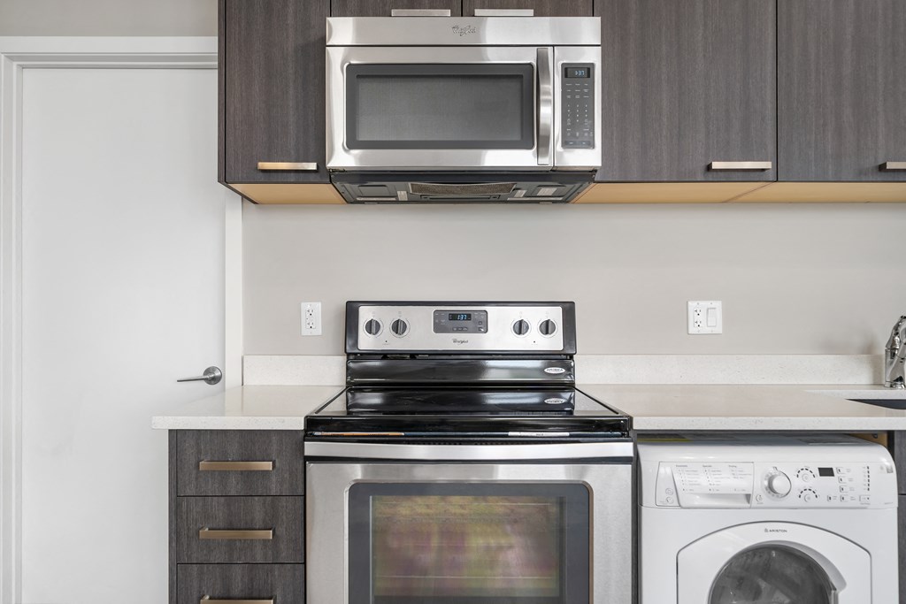 a kitchen with a stove and microwave and a washer and dryer