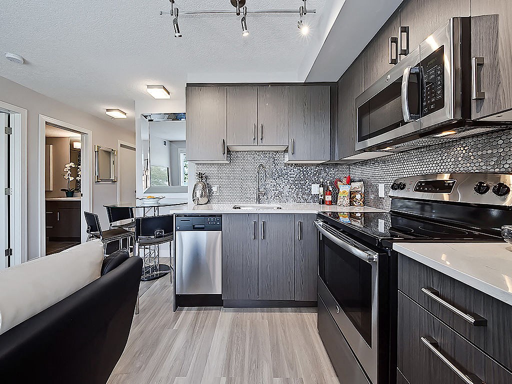 A modern kitchen with dark wood cabinets and stainless steel appliances.