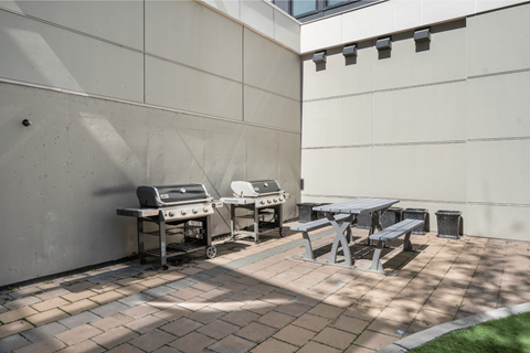 a patio with a picnic table and two gas bbqs
