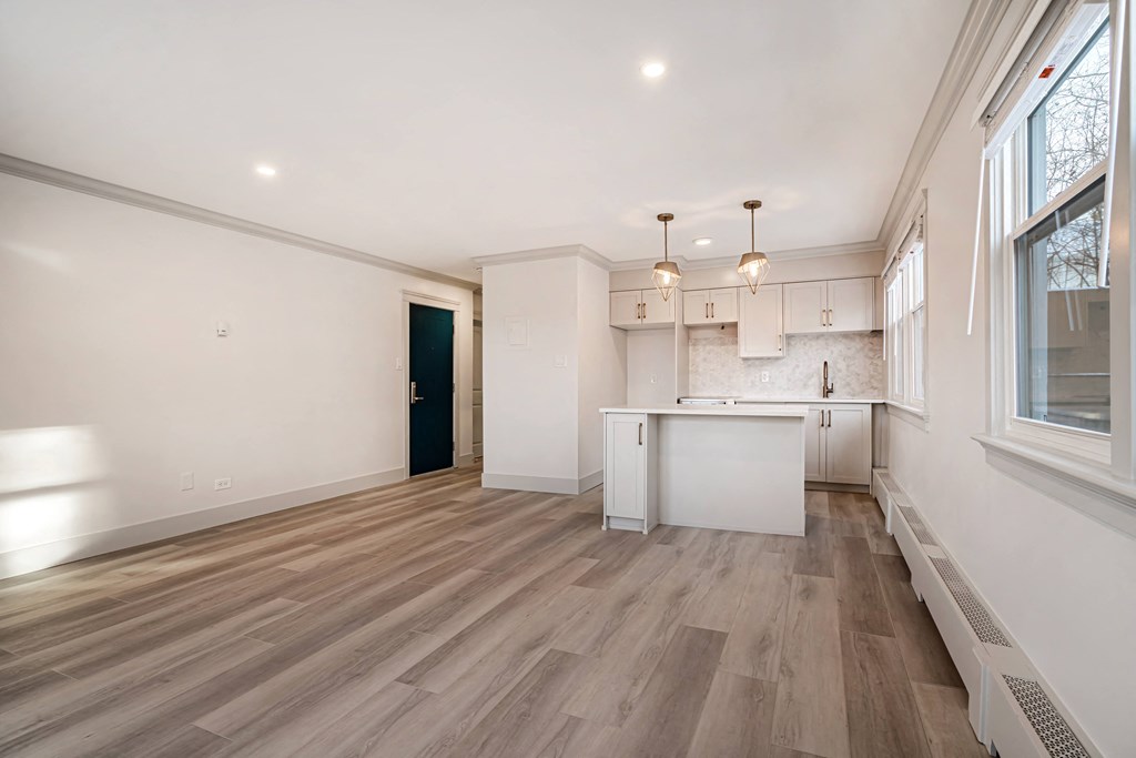 a living room and kitchen with white walls and wood floors