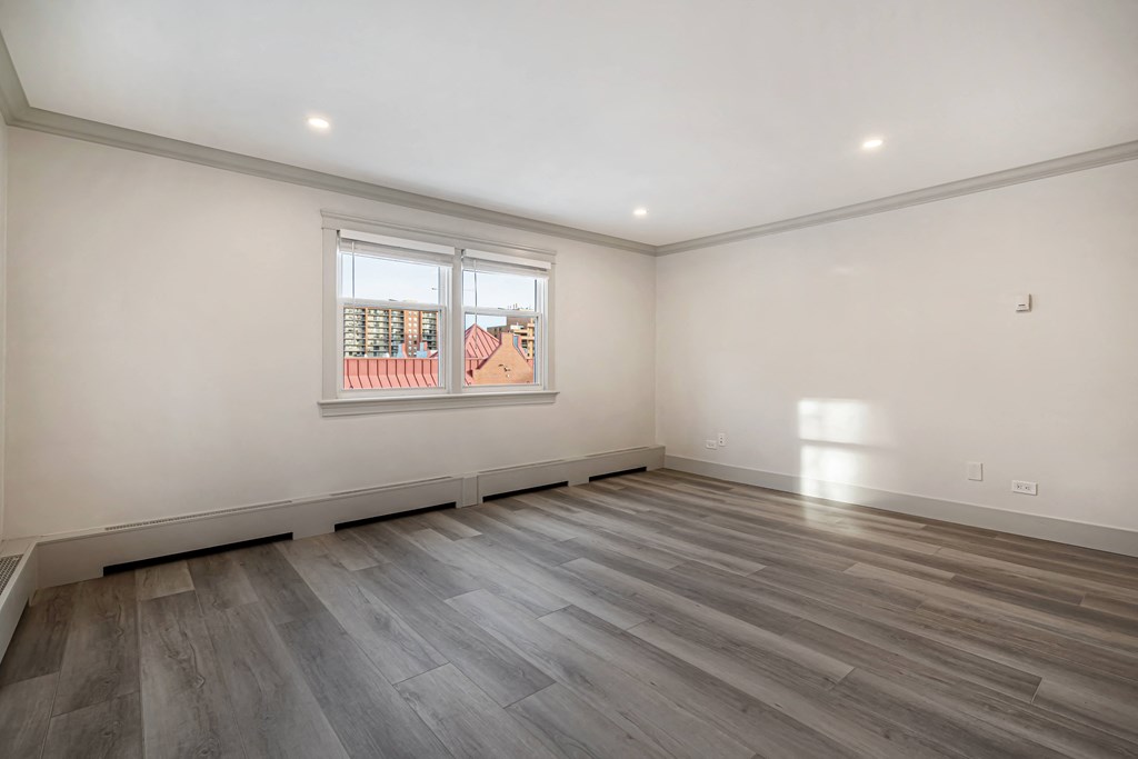 an empty living room with wood floors and a window