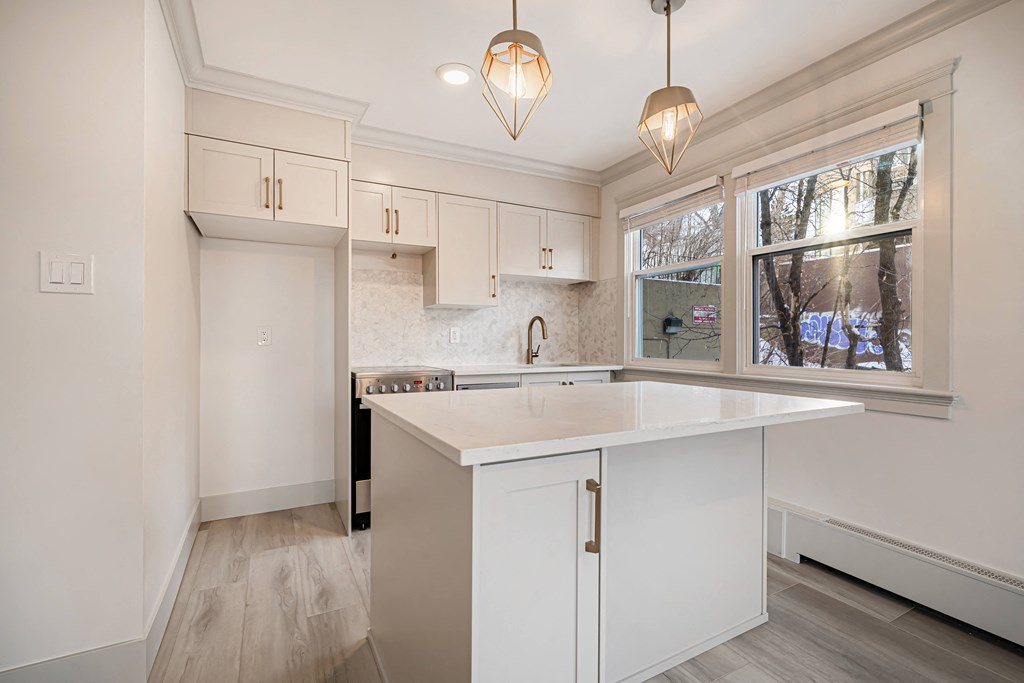 a kitchen with white cabinets and a large window