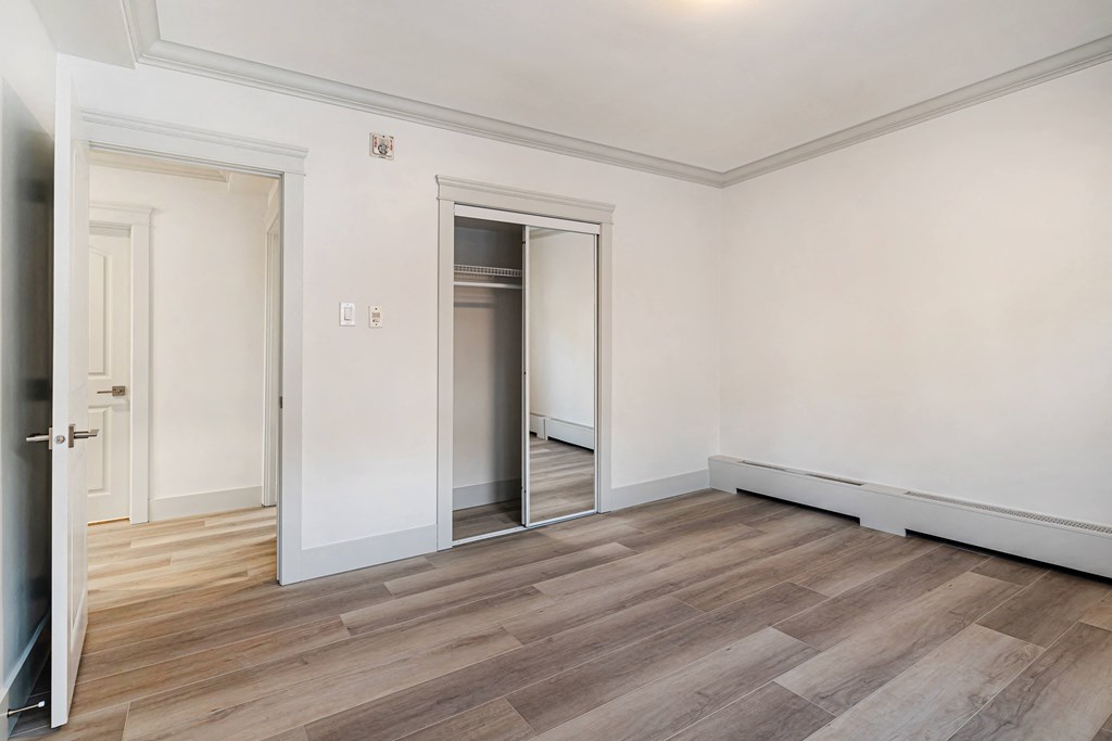 a living room with white walls and wood floors and a door to a closet