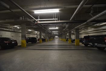 A parking garage with cars parked on both sides of the aisle.