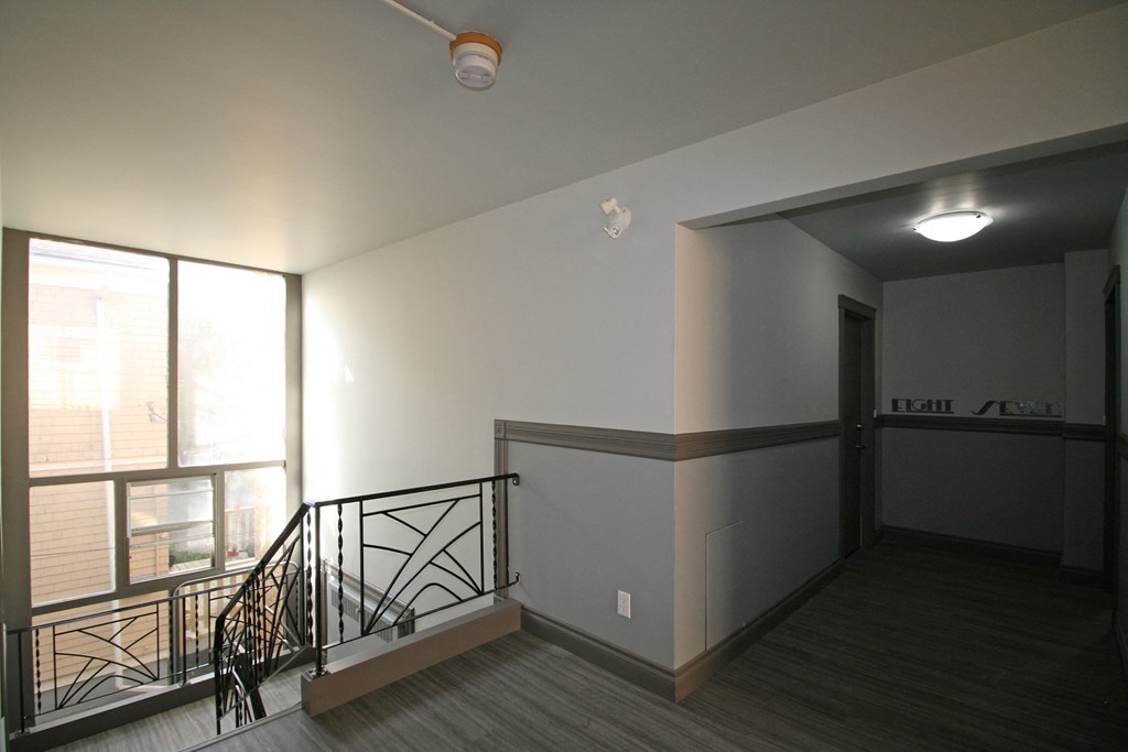 an empty living room with a staircase and a window