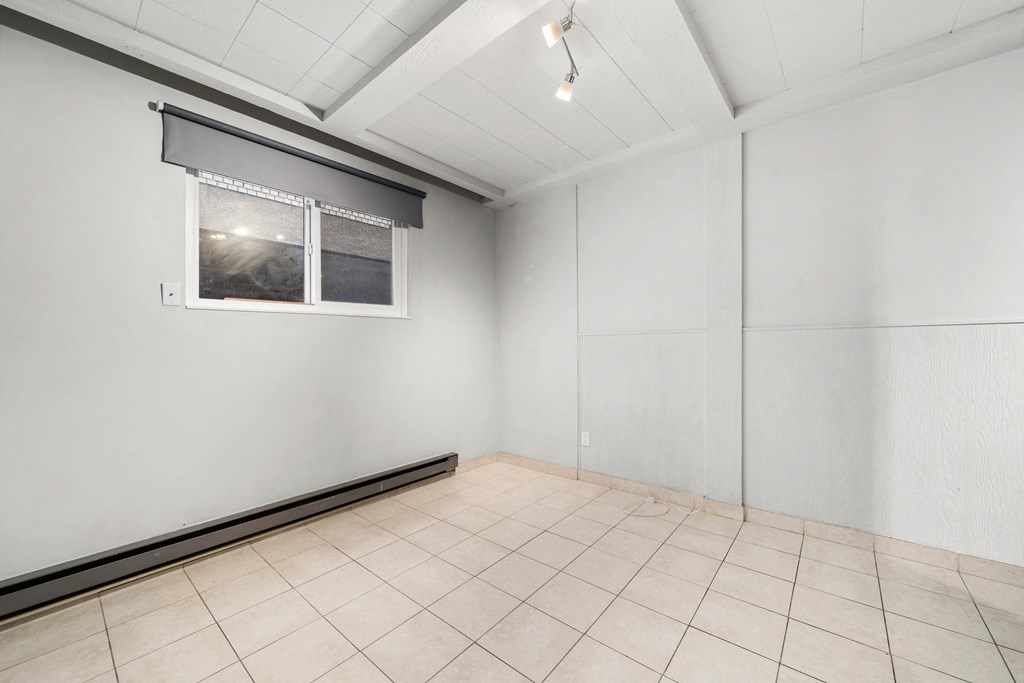 an empty room with a window and a tiled floor