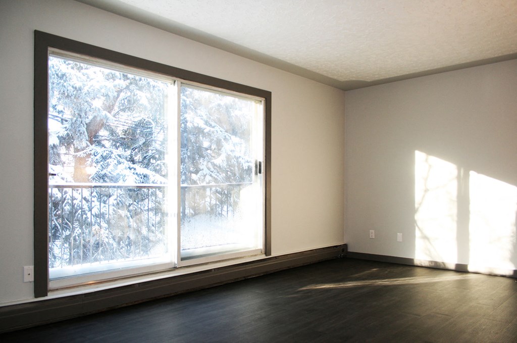 an empty living room with large window and wood floors