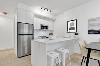 A modern kitchen with white cabinets and a stainless steel refrigerator.