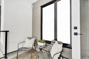 A small balcony with two chairs and a table.