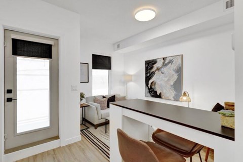 A modern living room with a white sofa and a large painting on the wall.