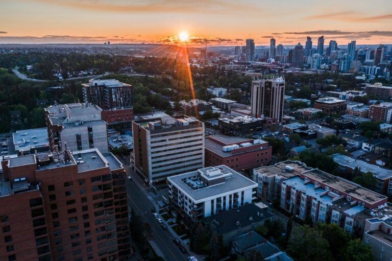 A cityscape with buildings and a sunset in the background.