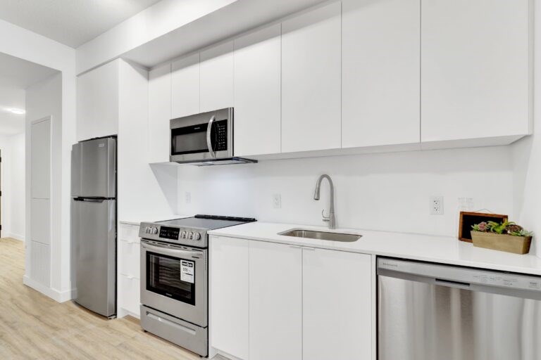A modern kitchen with white cabinets and stainless steel appliances.
