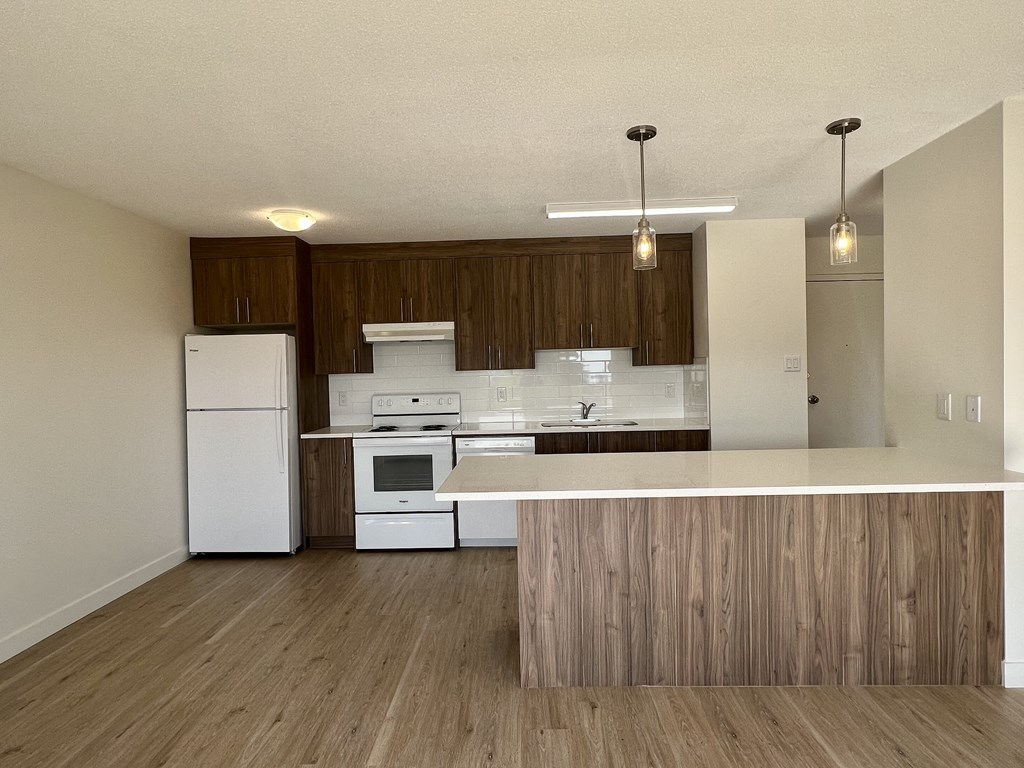 an empty kitchen with white appliances and wooden cabinets