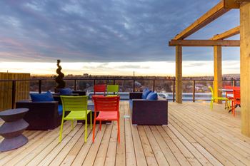 A wooden deck with colorful chairs and a table.