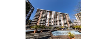 A large apartment building with a pool in front.
