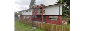 A red and white house with a wooden fence in front.