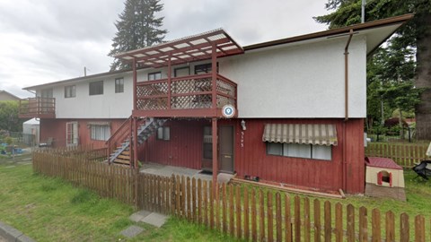 A red and white house with a wooden fence in front.