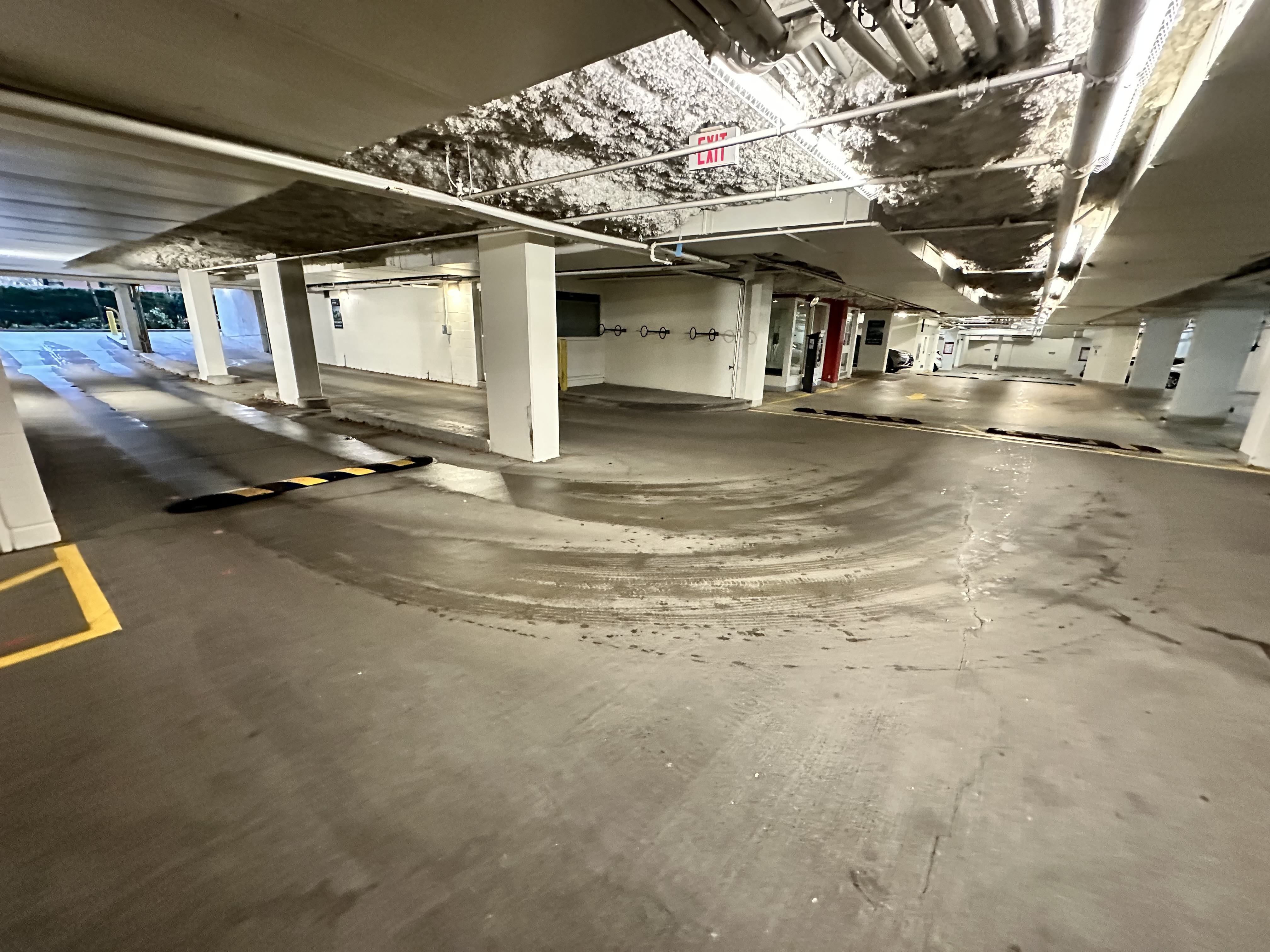 A parking garage with a concrete floor and white pillars.