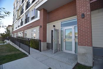 A brick building with a black fence and a glass door.