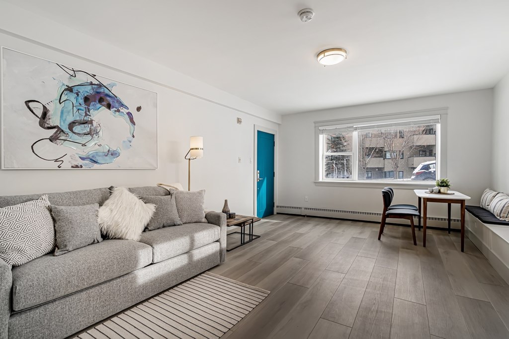A living room with a grey couch and a painting on the wall.