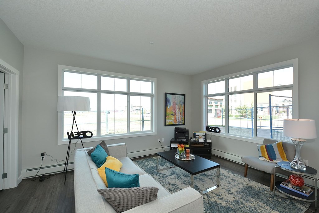 A living room with a white couch, a black coffee table, and a large window.