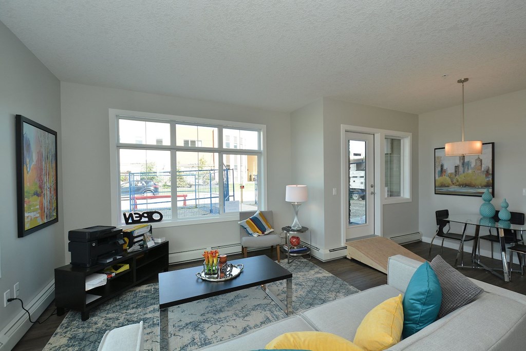 A living room with a grey couch, a coffee table, and a large window.